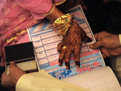 An Indian Muslim bride puts a thumb impression on a Marriage Certificate in the presence of religious leaders and a relative during the "Nikah Kabool Hai" or "Do You Agree for the Marriage" section of a mass wedding ceremony in Ahmedabad on October 24, 2010. Some 65 Muslim couples participated …