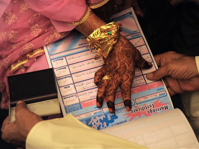 An Indian Muslim bride puts a thumb impression on a Marriage Certificate in the presence o