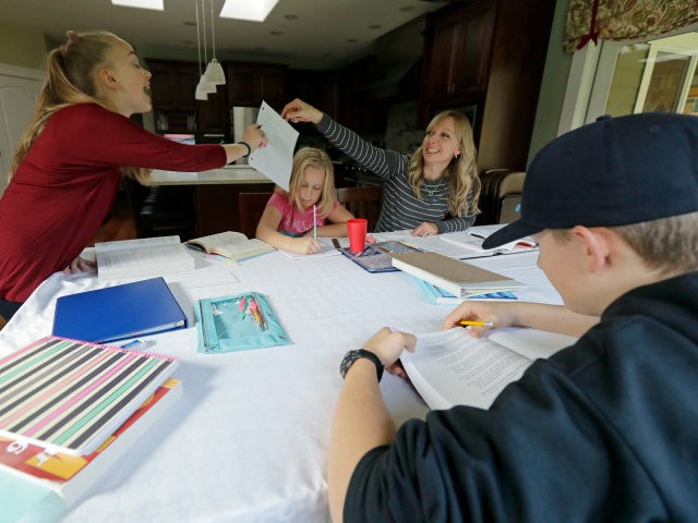 In this Oct. 9, 2019 photo, Donya Grant, upper right, works on homeschool lessons with her children, Rowyn, 11, left, Mabry, 8, second from left, and Kemper, 14, right, in their home in Monroe, Wash. The family joined a lawsuit against the Monroe School District and others, alleging that the …