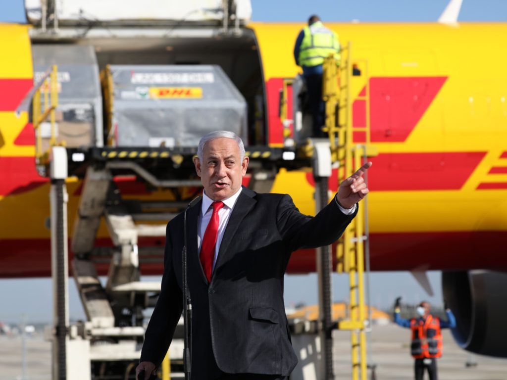 Israeli Prime Minister Benjamin Netanyahu gestures during a ceremony to mark the arrival of a plane of the international courier company DHL, carrying over 100,000 of doses of the first batch of Pfizer vaccines which landed at Ben Gurion Airport near Tel Aviv, on December 9, 2020. - According to media reports, the launch of a national COVID-19 immunisation campaign is set to begin on December 20. (Photo by Abir SULTAN / POOL / AFP) (Photo by ABIR SULTAN/POOL/AFP via Getty Images)