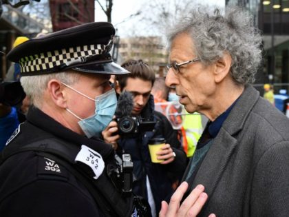 A police officer asks Piers Corbyn (R), brother of former Labour Party leader Jeremy Corbyn, to leave an anti-vaccine demonstration outside the offices of the Bill and Melinda Gates foundation in central London on November 24, 2020. - British Prime Minister Boris Johnson told MPs that thanks to a potential …