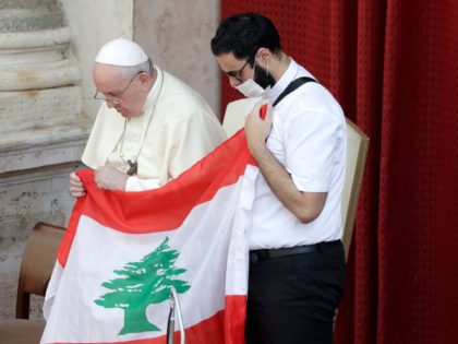 Pope Francis is flanked by Lebanese priest Georges Breidi as they hold a Lebanese flag in remembrance of last month's explosion in Beirut, during the pontiff's general audience, the first with faithful since February when the coronavirus outbreak broke out, at the San Damaso courtyard, at the Vatican, Wednesday, Sept. …
