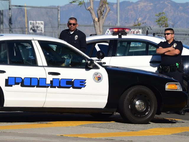 A police vehicle pulls up next to two officers standing at their vehicle outside a closed school near downtown Los Angeles on December 15, 2015. Los Angeles city officials on Tuesday defended their decision to shut down all public schools following a "credible" emailed threat, as authorities in New York …