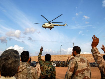 Members of the the "Saiqa" (Special Forces) of the self-proclaimed Libyan National Army (LNA), loyal to eastern strongman Khalifa Haftar, cheer as above flies a Russian-made Libyan Mil Mi-8 helicopter during an event in tribute to the unit's late commander General Wanis Bukhamada, who died a week prior, in the …
