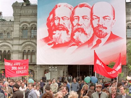 Women walk during May day official demonstration in Red Square, under portraits of Marx, E