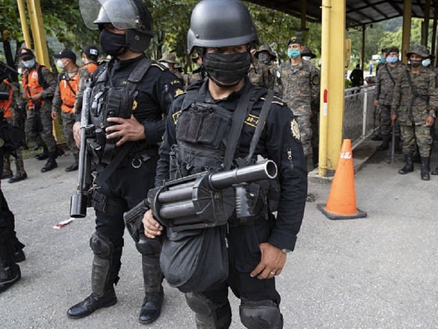 Security forces block the way to Honduran migrants in Poptun, Guatemala, Friday, Oct. 2, 2020. Guatemala vowed to detain and return members of a new caravan of hundreds of migrants that set out from neighboring Honduras in hopes of reaching the United States, saying they represent a health threat amid …
