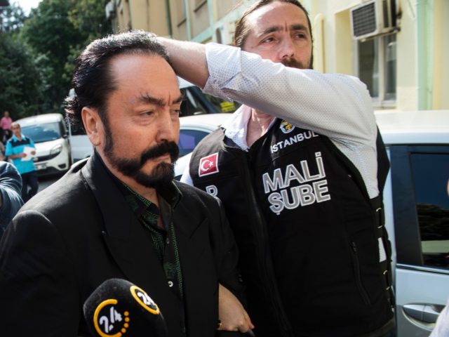 Turkish police officers escort televangelist and leader of a sect, Adnan Oktar (C) on July 11, 2018, in Istanbul, as he is arrested on fraud charges. - Turkish police detained the televangelist on fraud charges on July 11, 2018, notorious for propagating conservative views while surrounded by scantily-clad women he …