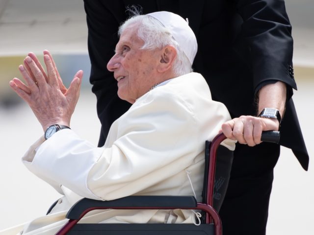 Former pope Benedict XVI sitting in a wheelchair smiles at the airport in Munich, southern