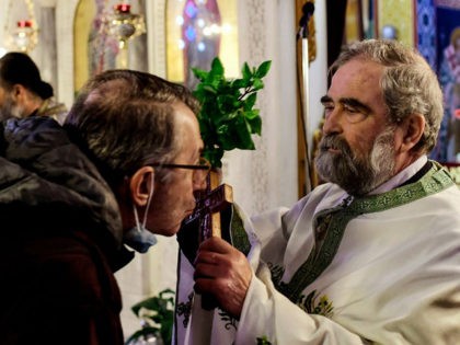 A faithfull kisses a cross during a service at a church in the Greek town of Corinth on January 6, 2021 as Greek bishops' determination to keep churches open for Epiphany holiday in the face of a coronavirus lockdown have stepped up a confrontation with the government over health restrictions. …