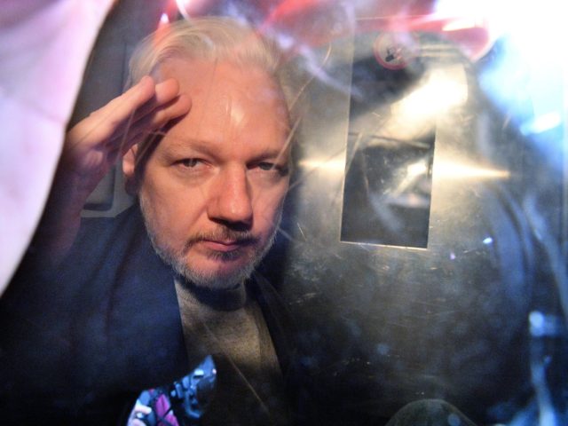 WikiLeaks founder Julian Assange gestures from the window of a prison van as he is driven