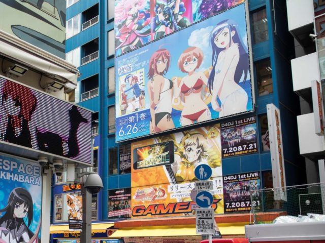 People walk past images of anime and manga characters in the Akihabara district in Tokyo on July 19, 2019. - The devastating apparent arson attack on a well-respected Japanese animation firm Kyoto Animation in Kyoto on July 18 which killed at least 33 people has left anime fans and industry …