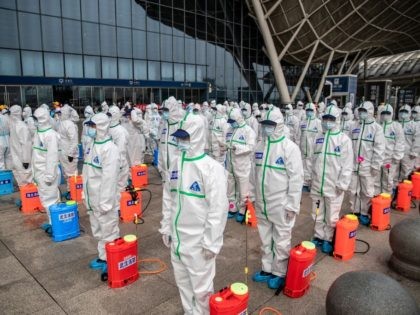 TOPSHOT - Staff members line up at attention as they prepare to spray disinfectant at Wuha