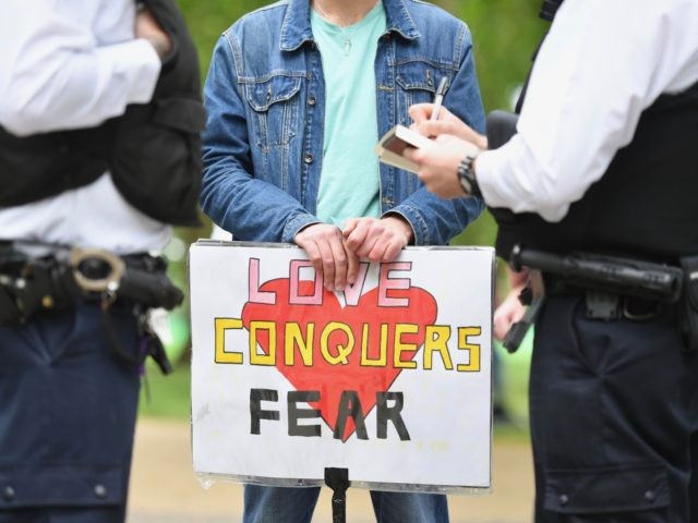 Police take details as a man holding a placard that reads "love conquers fear" attends an anti-coronavirus lockdown demonstration in Hyde Park in London on May 16, 2020, following an easing of lockdown rules in England during the novel coronavirus COVID-19 pandemic. - Fliers advertising 'mass gatherings' organised by the …