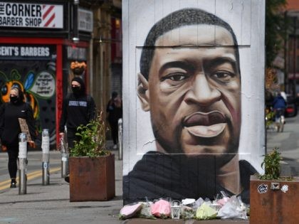 Flowers are seen beneath a mural of George Floyd, by street artist Akse, ahead of a demonstration in Manchester, northern England, on June 6, 2020, to show solidarity with the Black Lives Matter movement in the wake of the killing of George Floyd, an unarmed black man who died after …