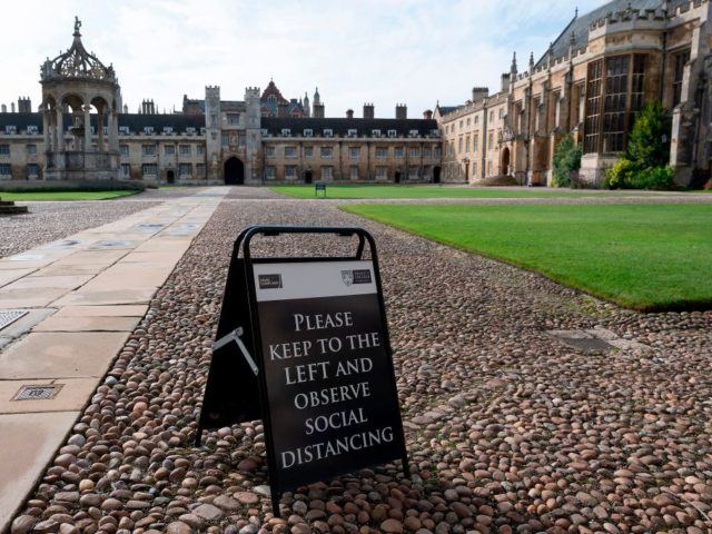 A sign advising people to social distance is displayed on the Great Court at Trinity Colle