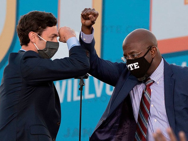 Democratic candidates for Senate Jon Ossoff (L) and Raphael Warnock (R) bump elbows on stage during a rally with US President-elect Joe Biden outside Center Parc Stadium in Atlanta, Georgia, on January 4, 2021. - President Donald Trump, still seeking ways to reverse his election defeat, and President-elect Joe Biden …