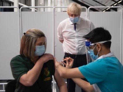 Britain's Prime Minister Boris Johnson watches as an individual is injected with a Covid-2