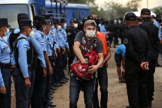 SAN PEDRO SULA, HONDURAS - JANUARY 15: A member of the migrant caravan searches his backpack for his identity document at a Honduran police checkpoint as the caravan heads to the Guatemalan border on January 15, 2021 in San Pedro Sula, Honduras. The caravan plans to walk across Guatemala and Mexico to eventually reach the United States. Central Americans expect to receive asylum and most Hondurans decided to migrate after being hit by recent hurricanes Eta and Iota. Honduras recently asked to U.S. to extend their Temporary Protected Status. (Photo by Milo Espinoza/Getty Images)