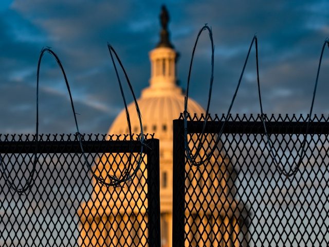 WASHINGTON, DC - JANUARY 16: The U.S. Capitol is seen behind a fence with razor wire durin