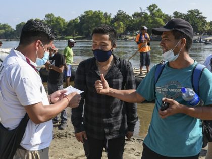 An officers of the National Institute of Migration of Mexico (INM) checks documentation of people who cross the Suchiate River from Guatemala to Mexico on January 16, 2021 as a new migrant caravan is expected to get to the Mexican border with Guatemala. - The Mexican government said it would …