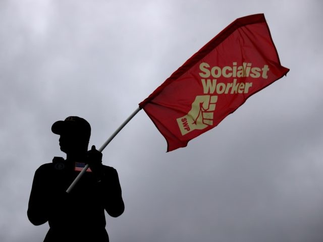 LONDON, UNITED KINGDOM - JUNE 06: A man holds a Socialist Worker flag as he stands on a bu