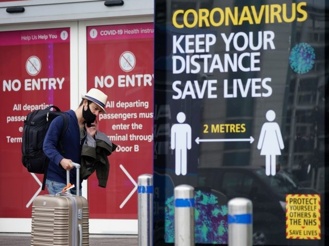 BIRMINGHAM, ENGLAND - JULY 27: Passengers wearing protective masks exit the arrivals terminal at Birmingham Airport on July 27, 2020 in Birmingham, England. On Sunday the British government, concerned by a spike in coronavirus cases in Spain, reimposed a requirement for travelers returning from that country to self-isolate for 14 …