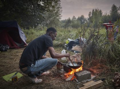 CALAIS, FRANCE - AUGUST 15: A refugee cooks on a small fire in a makeshift camp in wasteland on the outskirts of Calais after recent evictions by police at previously established camps have forced refugees to more remote areas on August 15, 2020 in Calais, France. A spate of good …
