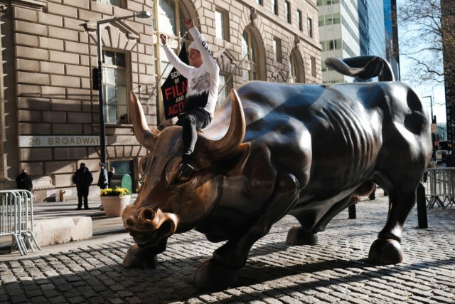 NEW YORK, NEW YORK - NOVEMBER 24: A man sits on the Wall street bull near the New York Sto