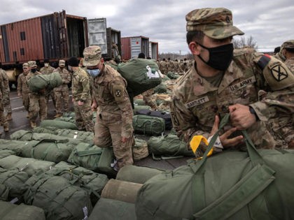 FORT DRUM, NEW YORK - DECEMBER 10: U.S. Army soldiers retrieve their duffel bags after they returned home from a 9-month deployment to Afghanistan on December 10, 2020 at Fort Drum, New York. The 10th Mountain Division soldiers who arrived this week are under orders to isolate with family at …