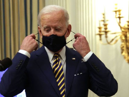 WASHINGTON, DC - JANUARY 22: U.S. President Joe Biden takes of his mask as he arrives at a