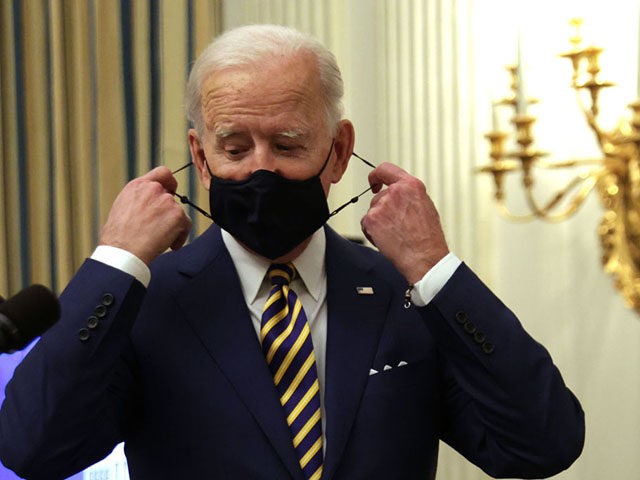 WASHINGTON, DC - JANUARY 22: U.S. President Joe Biden takes of his mask as he arrives at an event on economic crisis in the State Dining Room of the White House January 22, 2021 in Washington, DC. President Biden spoke on his administration’s response to the economic crisis that caused …