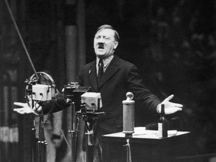 1935: Nazi leader Adolf Hitler speaks in front of microphones and gestures with his hands.