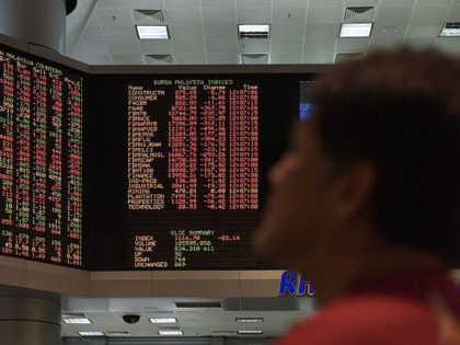 A trader watches electronic boards showing stock movements at the Malaysia Stock Exchange in Kuala Lumpur on June 24, 2016.