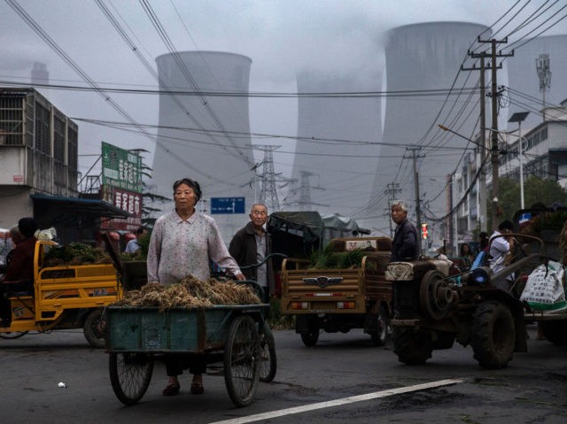 HUAINAN, CHINA - JUNE 13: Chinese street vendors sell vegetables at a local market outside a state owned Coal fired power plant near the site of a large floating solar farm project under construction by the Sungrow Power Supply Company on a lake caused by a collapsed and flooded coal …