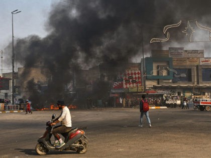 Iraqi protesters are pictured next to burning tyres during clashes with police during anti