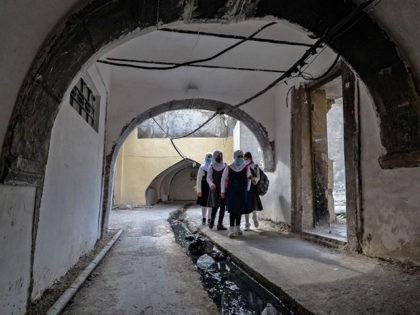 Iraqi pupils wearing protective masks walk to school on the first day of the new academic
