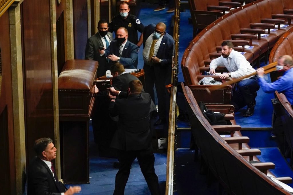 U.S. Rep. Troy Nehls charges the door of the House Chamber to defend against protesters trying to break in. (AP Photo: Andrew Harnik)