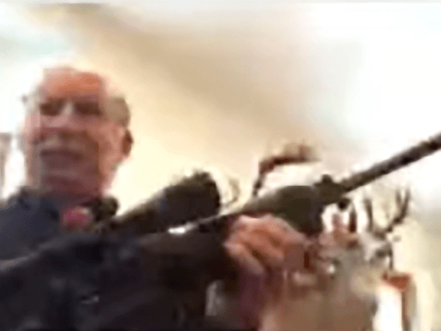 Grand Traverse County Commissioner Ron Clous holds a rifle at his home during a county com