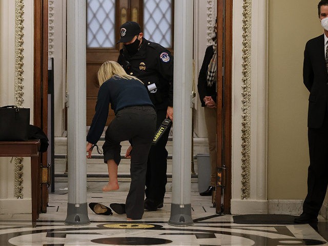 WASHINGTON, DC - JANUARY 12: Rep. Marjorie Taylor Greene (R-GA) removes her shoes after setting off the metal detector outside the doors to the House of Representatives Chamber on January 12, 2021 in Washington, DC. Today the House of Representatives plans to vote on Rep. Jamie Raskin's (D-MD) resolution calling …