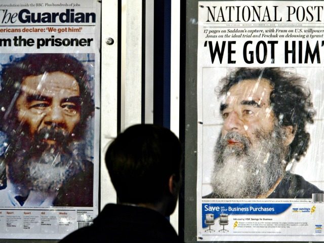 An unidentified man looks at the front pages of international newspapers on Monday, Dec. 15, 2003 in Washington. Saddam Hussein's capture has led to speculation about how the former Iraqi dictator will be tried. (AP Photo/Evan Vucci)