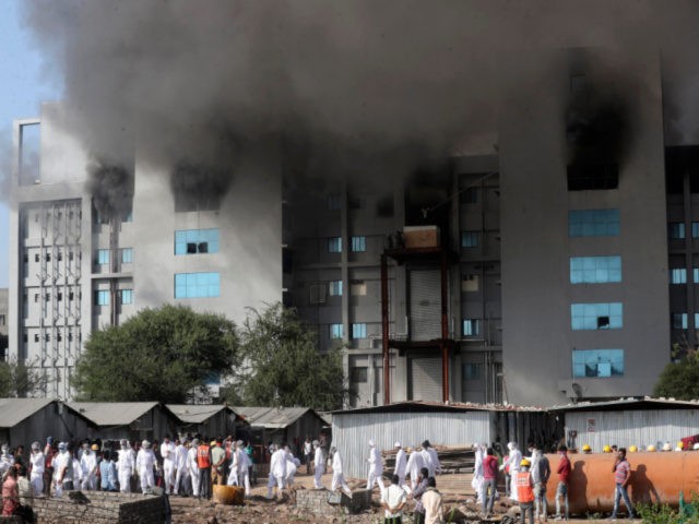 Employees leave as smoke rises from a fire at Serum Institute of India, the world's larges