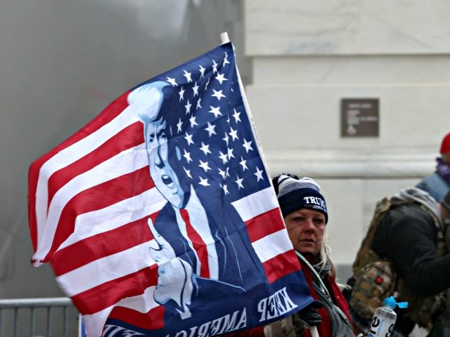 WASHINGTON, DC - JANUARY 06: A supporter holds a President Donald Trump flag as protesters gather on the U.S. Capitol Building on January 06, 2021 in Washington, DC. Pro-Trump protesters entered the U.S. Capitol building after mass demonstrations in the nation's capital during a joint session Congress to ratify President-elect …