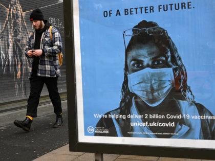 A pedestrian walks past a poster by the charity Unicef, promoting Covid-19 vaccines, in Manchester, north west England on January 5, 2021, as Britain enters a national lockdown to combat the spread of COVID-19. - England's six-week lockdown, which began at midnight, emulates the first national coronavirus curbs in place …