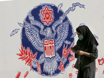 An Iranian woman walks past a mural painted on the outer walls of the former US embassy in the Iranian capital Tehran, on November 4, 2020 as the US waits for the results of the presidential election. (Photo by ATTA KENARE / AFP) (Photo by ATTA KENARE/AFP via Getty Images)