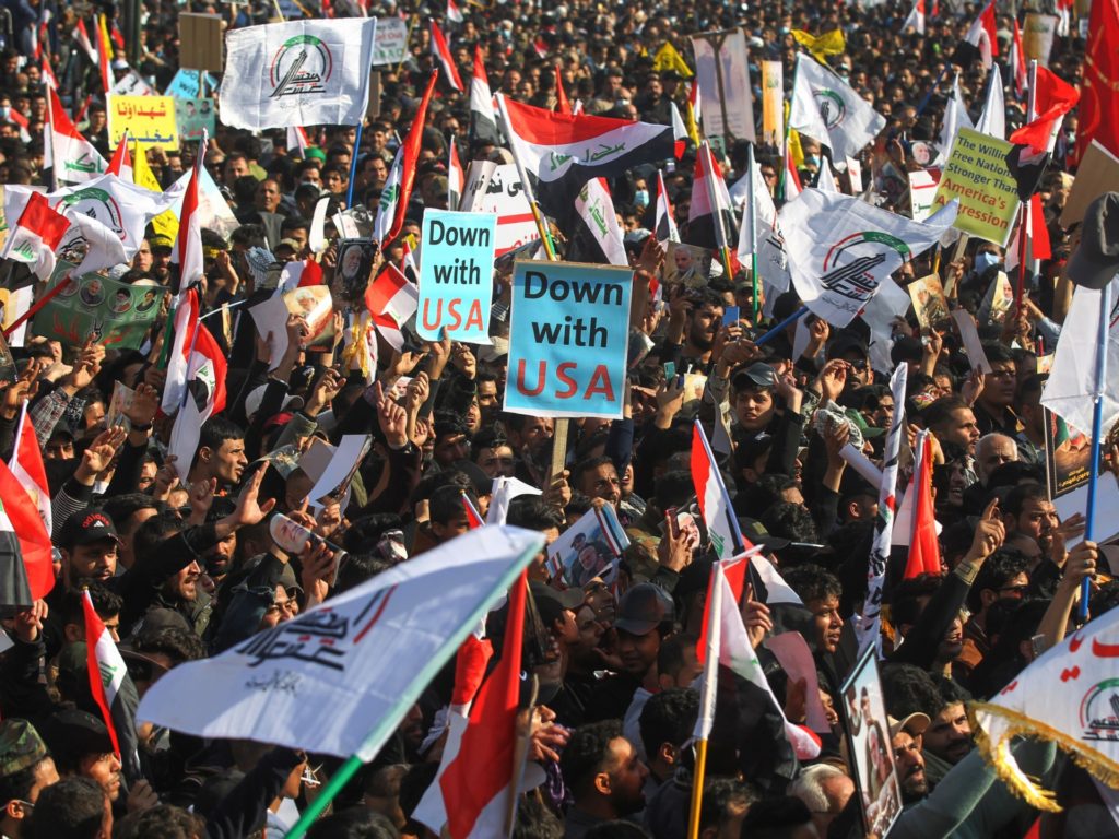 Iraqi demonstrators lift flags and placards as they rally in Tahrir square in the capital Baghdad on January 3, 2021, to mark one year after a US drone strike killed Iran's revered commander Qasem Soleimani and his Iraqi lieutenant Abu Mahdi al-Muhandis near the capital. (Photo by AHMAD AL-RUBAYE / AFP) (Photo by AHMAD AL-RUBAYE/AFP via Getty Images)