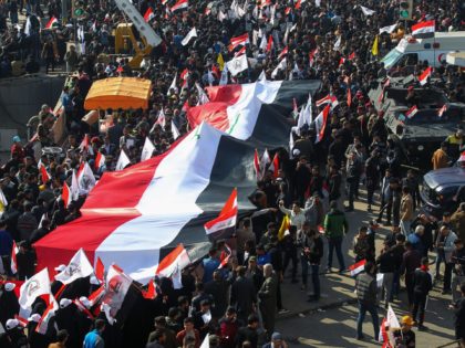 Iraqi demonstrators lift a giant national flag during a rally marking the first anniversary of the killing of Iraqi commander Abu Mahdi al-Muhandis (L) and Iranian Revolutionary Guards commander Qasem Soleimani, in Tahrir square in the capital Baghdad on January 3, 2021. - Thousands of Iraqi mourners chanted "revenge" and …