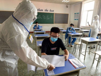 TOPSHOT - A staff member (L) distributes papers to a student at an isolation examination r