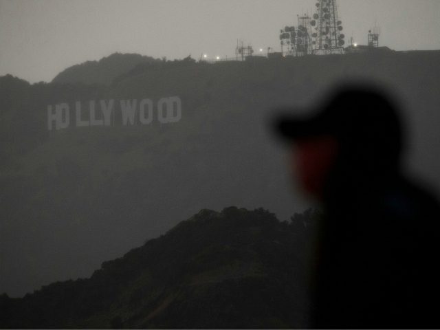 A person wearing a face mask looks from a viewing area overlooking the Hollywood sign shrouded by clouds during heavy rains as seen from the Griffith Observatory on December 28, 2020 in Los Angeles, California. - Los Angeles residents woke up to rain today as the first major storm of …