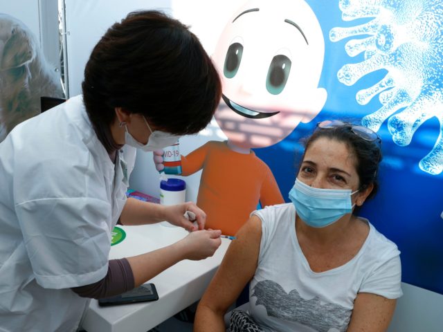 A healthcare worker administers a COVID-19 vaccine to an Israeli woman at Clalit Health Se
