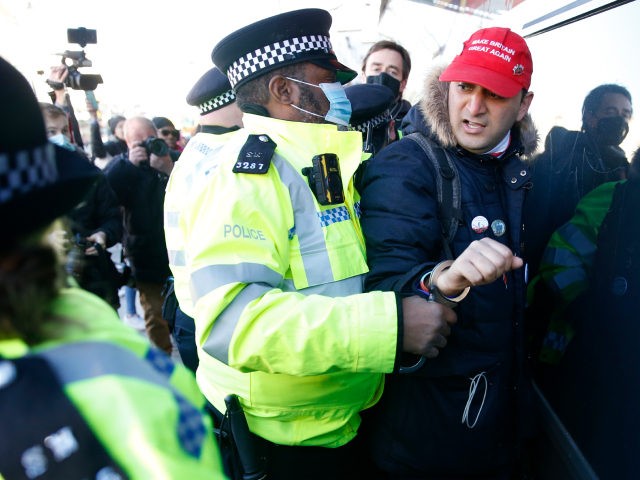 LONDON, ENGLAND - JANUARY 09: A protester wearing a "Make Britain Great Again" baseball cap is detained by Police on Clapham high street during the anti-lockdown demonstration on January 9, 2021 in London, England. Chief Medical Officer Chris Whitty has filmed an advert for HM Government warning that people should …